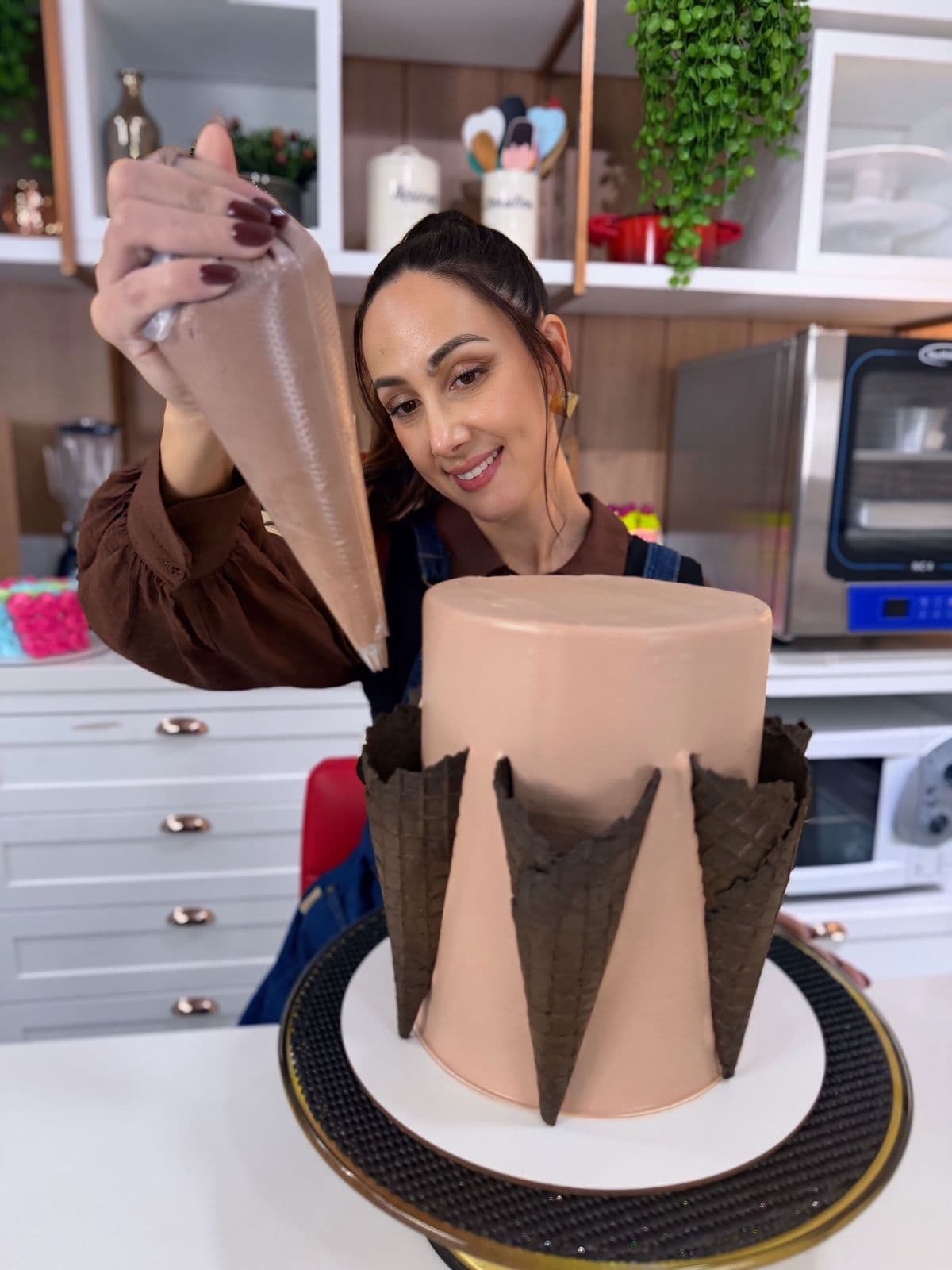 Bolo com casquinhas de chocolate sendo decorado no suporte giratório