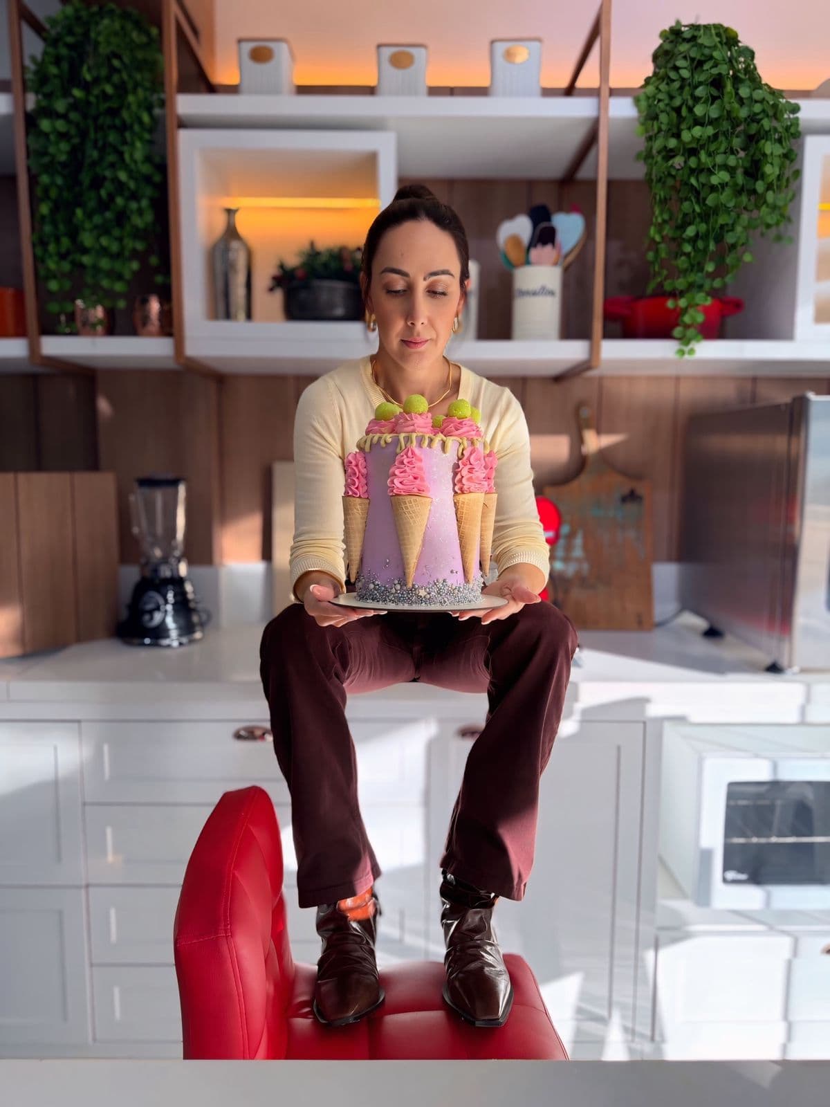 Confeiteira sentada com um bolo decorado no colo